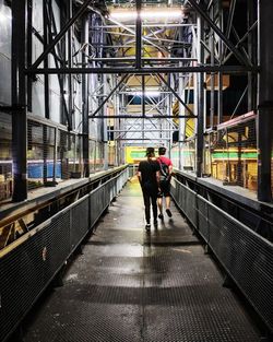 Rear view of men walking on footbridge in city