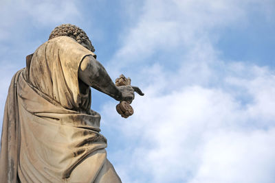Ancient statue of saint peter in key on the hand and blue sky and white clouds on background