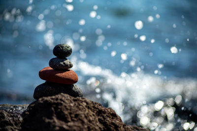 Closeup shot of pebbles stacked on each other in a balance with the blue sea in the background