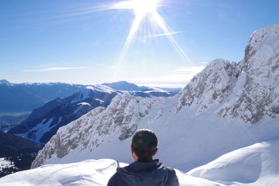 Rear view of woman on snowcapped mountain against sky