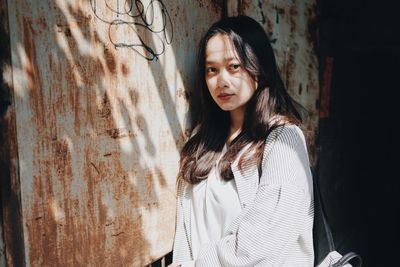 Woman looking away while standing against wall