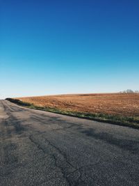 Country road against clear blue sky