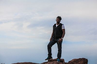 Full length portrait of young man standing against sky