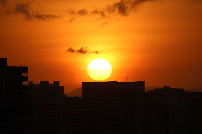 Silhouette buildings against orange sky during sunset