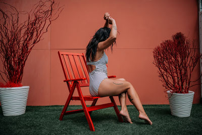 Side view of woman on chair against plants