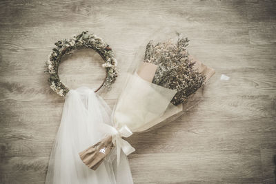 High angle view of wreath and bouquet with veil on hardwood floor