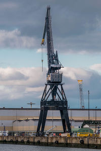 Cranes at pier against sky