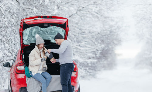 Rear view of man photographing woman using mobile phone