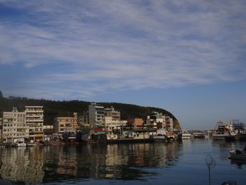 City buildings by river against sky