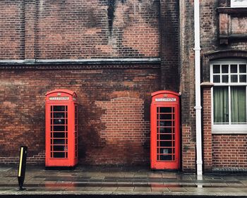 Red telephone booth against brick wall