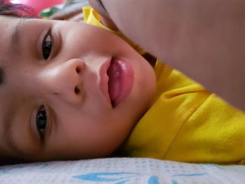 Close-up portrait of cute baby boy relaxing on bed at home