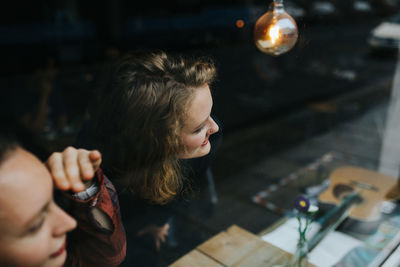 Close-up of women looking through window at cafe