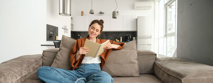 Portrait of woman using digital tablet while sitting on sofa at home