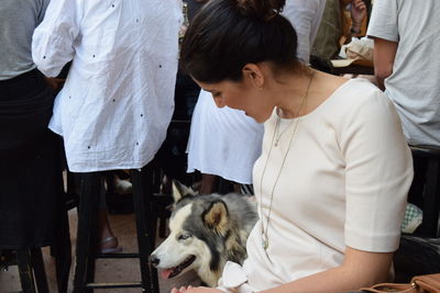 Young woman petting dog while sitting on chair