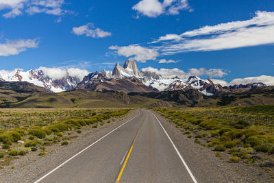 Road leading towards mountains against sky