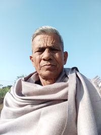 Portrait of senior man wearing shawl against clear sky