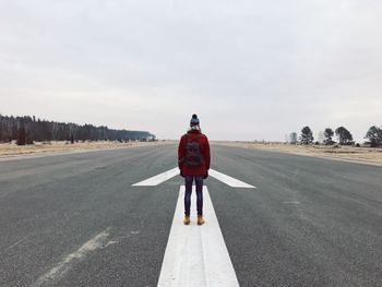 Rear view of woman standing on road against sky