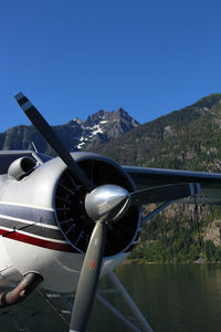 Seaplane over lake by mountains against sky