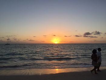 People walking on beach during sunset