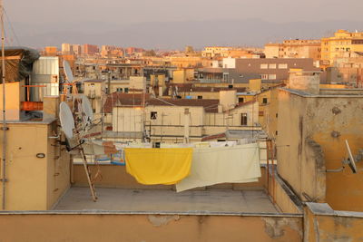 Yellow buildings by houses against sky in city