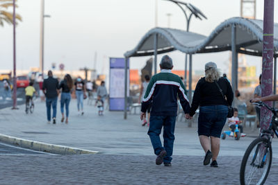 Rear view of people walking on street in city