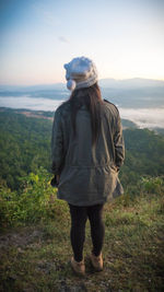 Rear view of woman standing on mountain against sky