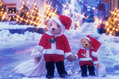 Close-up of teddy bears with santa costumes on snow covered road