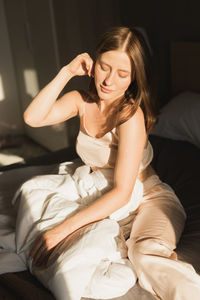 Young woman sitting on bed at home