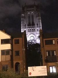 Low angle view of clock tower amidst buildings at night