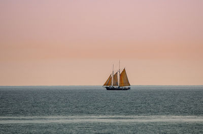 Sailboat sailing on sea against sky during sunset