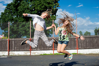 Full length of happy girls jumping in park