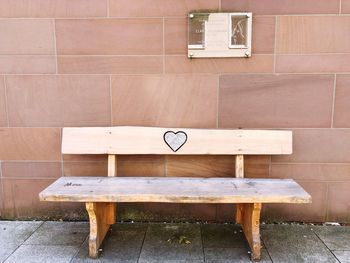 Empty bench on table against brick wall