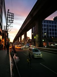 Cars on road in city against sky during sunset
