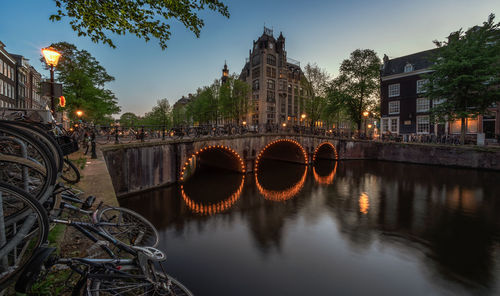 Bridge over river by buildings against sky