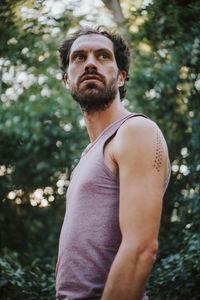 Portrait of young man standing against tree