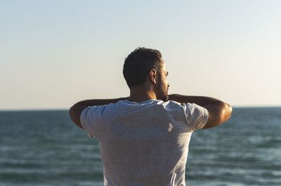 Rear view of man looking at sea against sky