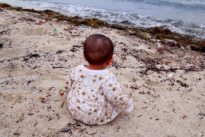 Rear view of baby boy sitting at beach