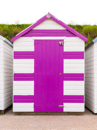 Colourful beach house or garden shed. beach hut with pink - purple painted door.