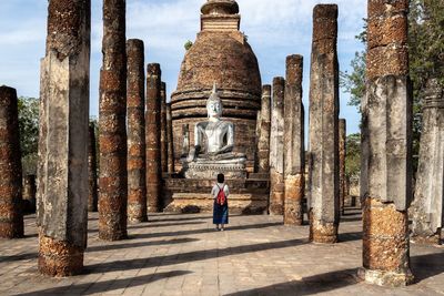 Woman walking against buddha statue in temple