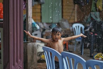 Portrait of boy with arms raised on rainy day