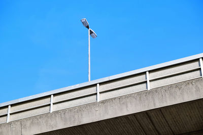 Low angle view of bird on building against clear blue sky