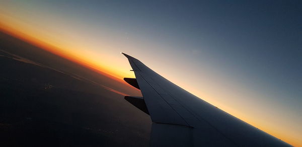 Airplane flying against sky during sunset