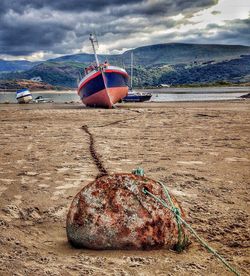 Boat moored on beach against sky