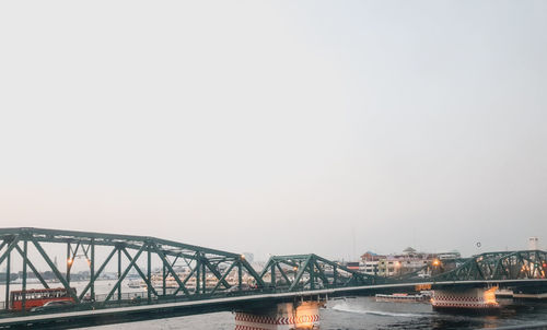 Bridge over river against sky in city