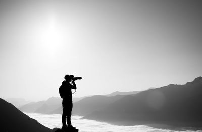 Silhouette man photographing mountain against sky