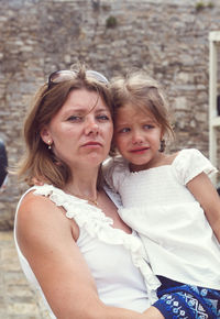 Portrait of mother holding daughter standing outdoors