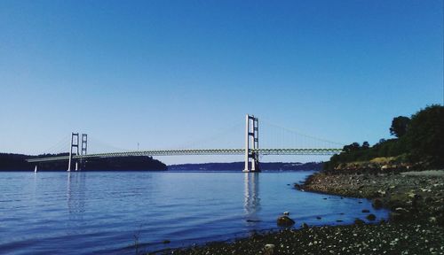 Suspension bridge over river against blue sky