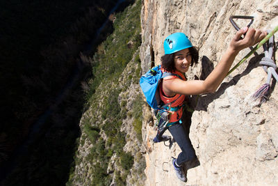 Young woman climbing through a via ferrata in chulilla canyon (spain)