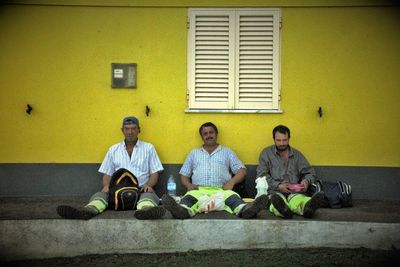 People sitting on yellow wall