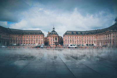 Buildings in city against cloudy sky